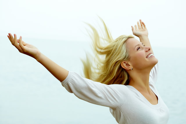 blonde haired girl with arms raised smiling