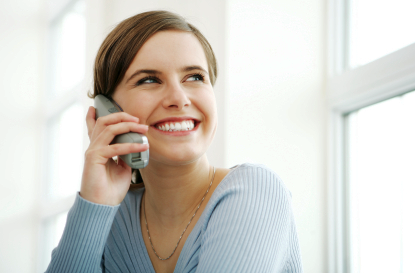 young lady in blue smiling and holding phone